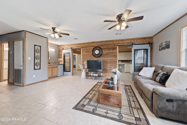 tiled living room with ceiling fan, a barn door, and wooden walls