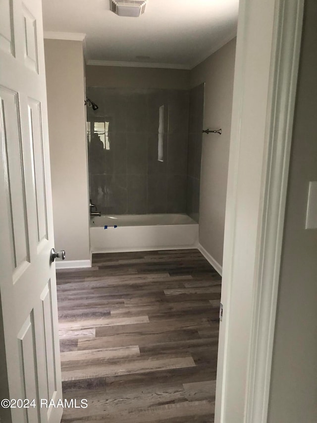 bathroom with crown molding, wood-type flooring, and tiled shower / bath combo