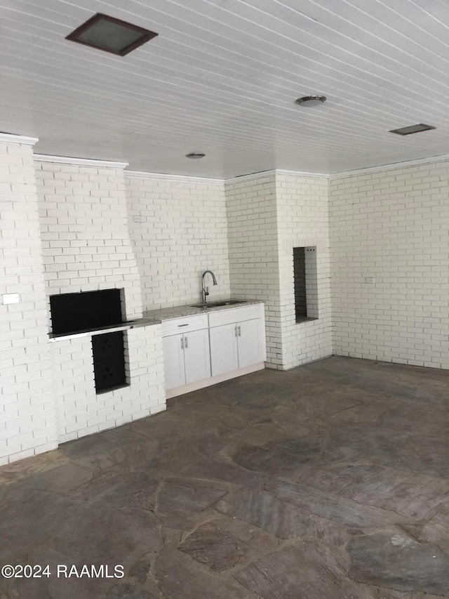 unfurnished living room featuring brick wall, wooden ceiling, and sink