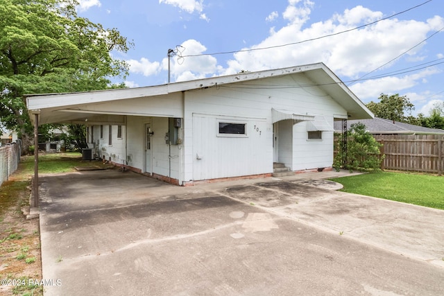 view of front of home featuring a carport, a front lawn, and central air condition unit