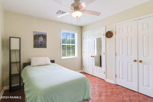 tiled bedroom featuring multiple closets and ceiling fan