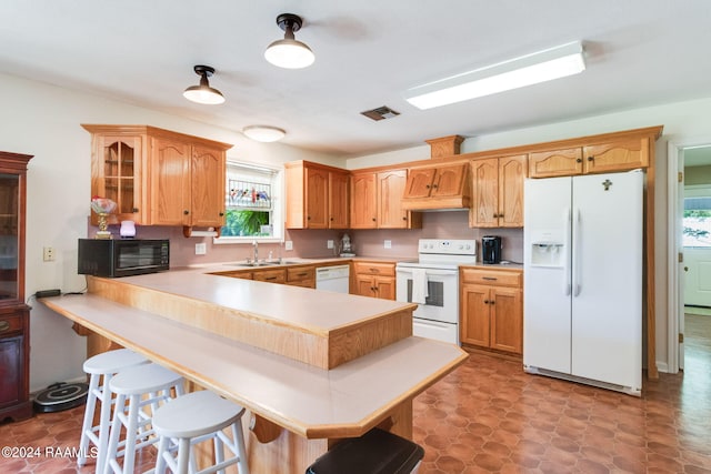 kitchen with premium range hood, white appliances, light tile flooring, kitchen peninsula, and sink