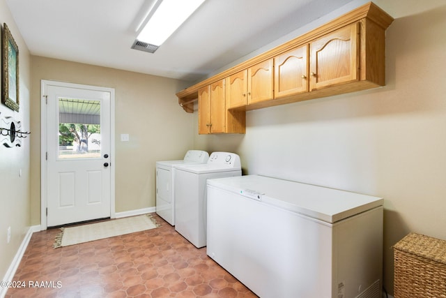 washroom featuring cabinets, washing machine and dryer, and light tile floors