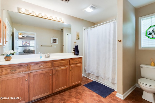 bathroom featuring a healthy amount of sunlight, vanity, toilet, and tile flooring