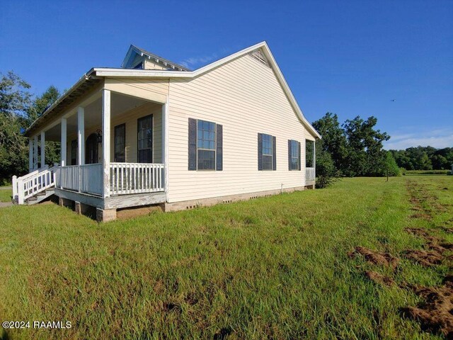 view of side of home with a lawn and covered porch