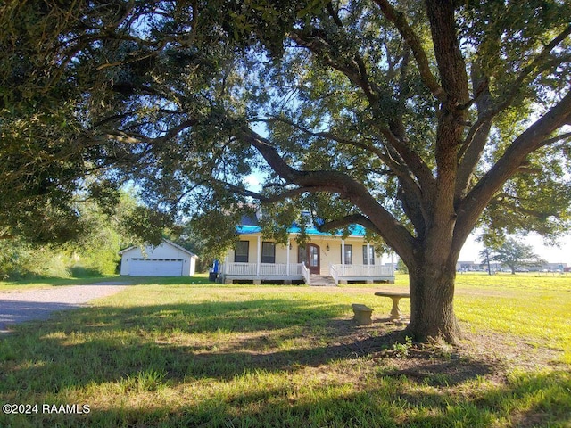 single story home featuring a garage, a front yard, a porch, and an outbuilding