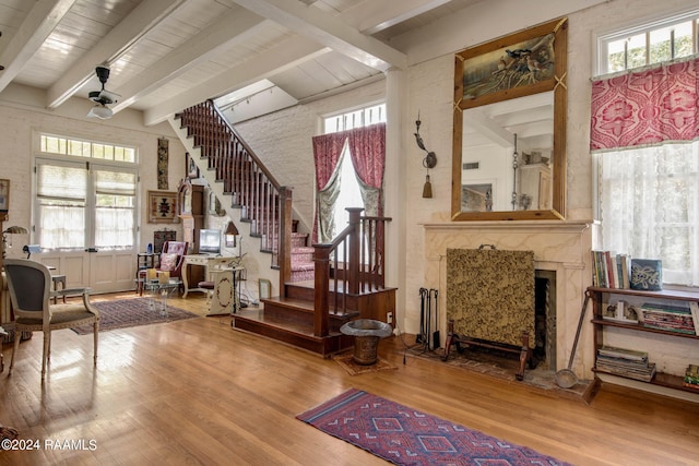 interior space with hardwood / wood-style flooring, a high end fireplace, beamed ceiling, and ceiling fan