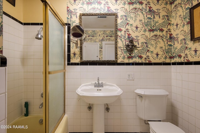 bathroom with backsplash, enclosed tub / shower combo, toilet, and tile walls