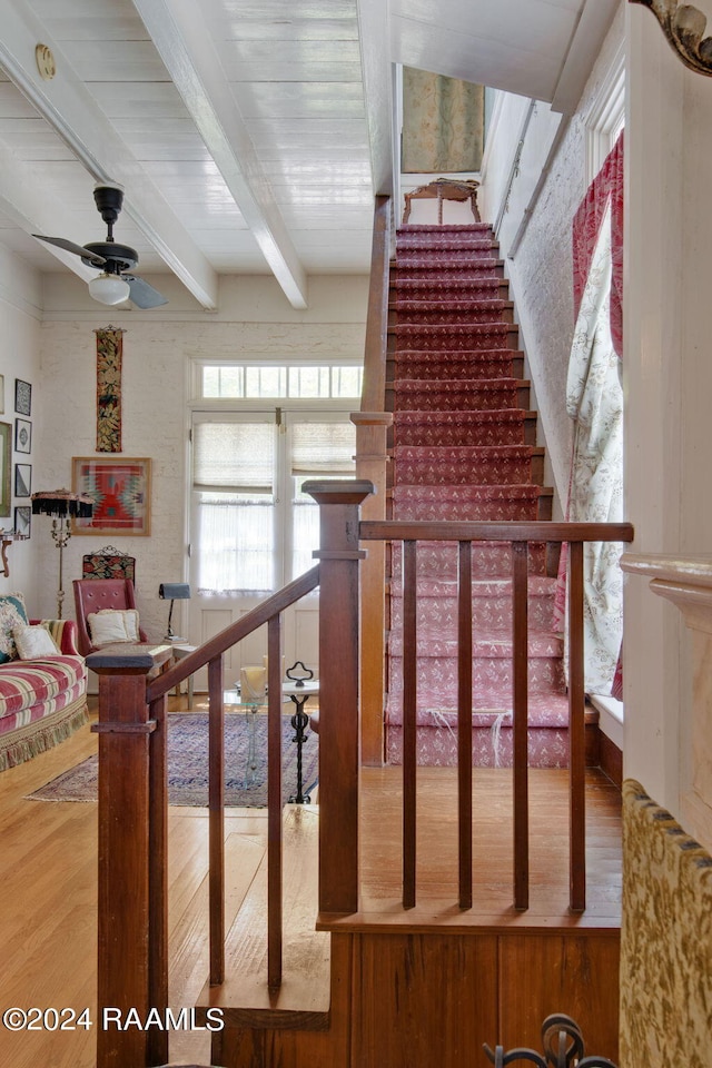 stairway with beamed ceiling, ceiling fan, and hardwood / wood-style flooring