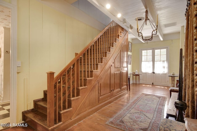 staircase featuring wood ceiling, wood-type flooring, and beamed ceiling