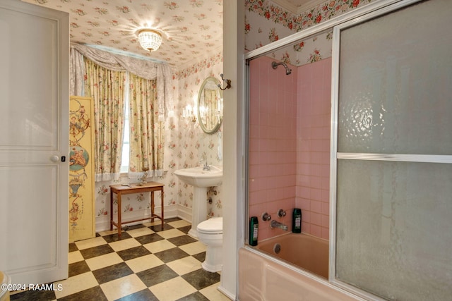 bathroom with tile floors, toilet, and bath / shower combo with glass door