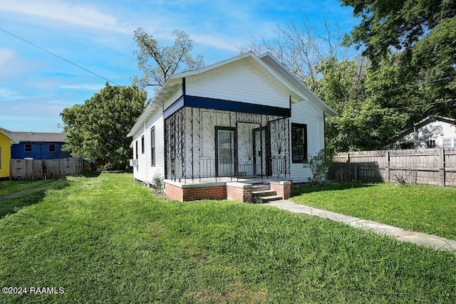 back of house with covered porch and a yard