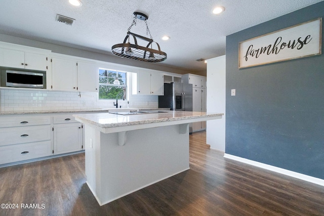 kitchen with tasteful backsplash, white cabinetry, a kitchen island, and dark hardwood / wood-style floors