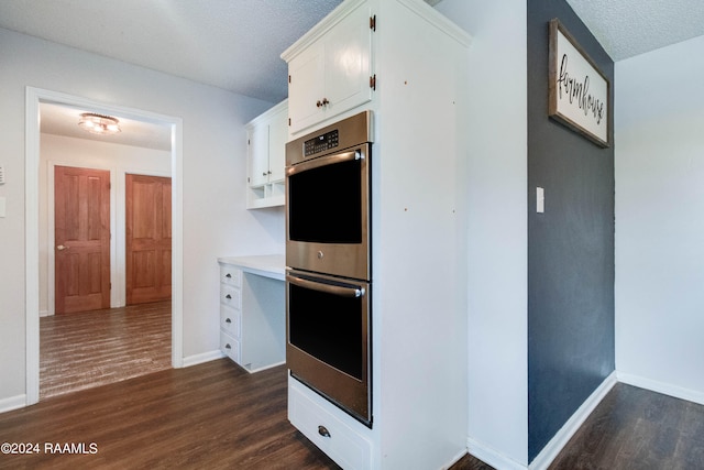 kitchen featuring stainless steel double oven, dark wood-type flooring, and white cabinets