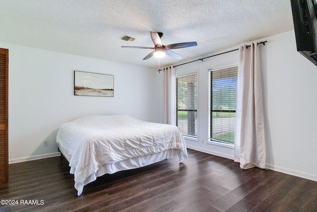 bedroom with ceiling fan, dark wood-type flooring, and a textured ceiling