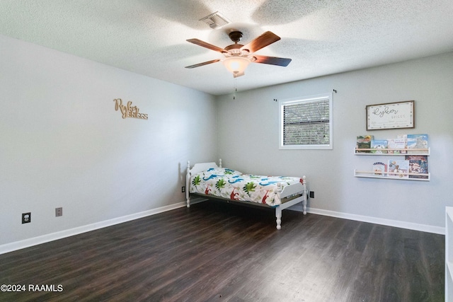 bedroom with dark hardwood / wood-style flooring, ceiling fan, and a textured ceiling