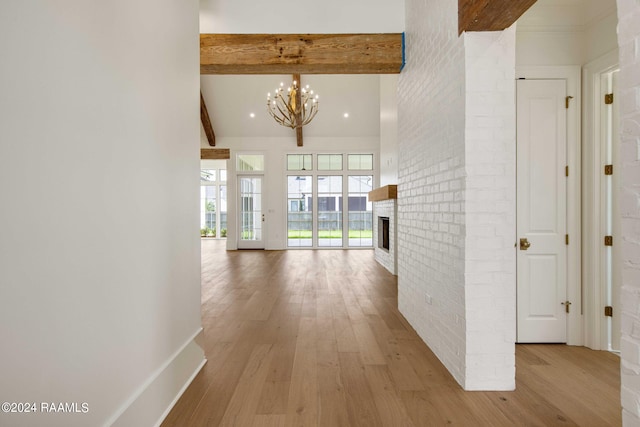 corridor featuring brick wall, light hardwood / wood-style flooring, beam ceiling, and a notable chandelier