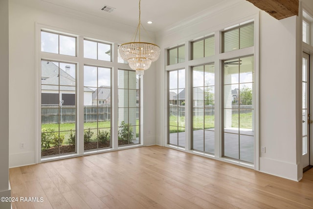 doorway to outside featuring light hardwood / wood-style floors, crown molding, and a chandelier