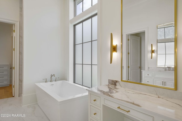 bathroom with vanity, a wealth of natural light, and a relaxing tiled tub