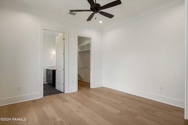 unfurnished bedroom with hardwood / wood-style floors, a walk in closet, connected bathroom, a closet, and ceiling fan