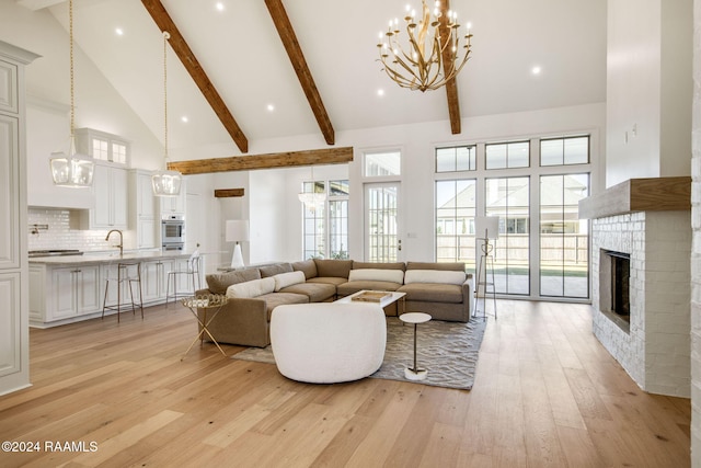 living room featuring light hardwood / wood-style floors, a brick fireplace, sink, high vaulted ceiling, and beamed ceiling