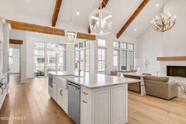 kitchen with pendant lighting, white cabinetry, high vaulted ceiling, stainless steel dishwasher, and a center island with sink