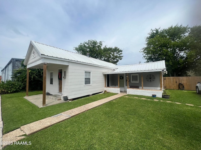 rear view of house featuring covered porch and a yard