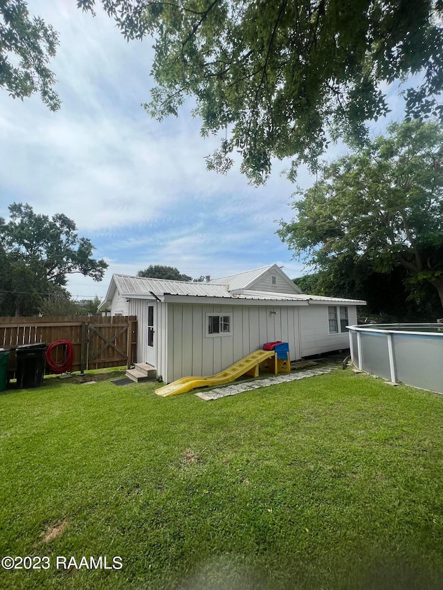 rear view of property with a fenced in pool and a lawn