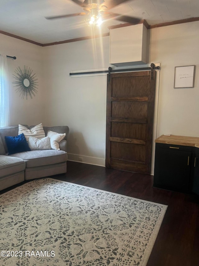 living room featuring ornamental molding, a barn door, ceiling fan, and dark hardwood / wood-style floors