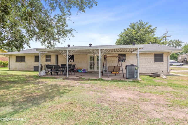 rear view of house with central AC, a patio area, and a lawn