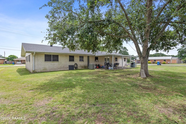 rear view of property featuring central AC unit and a lawn