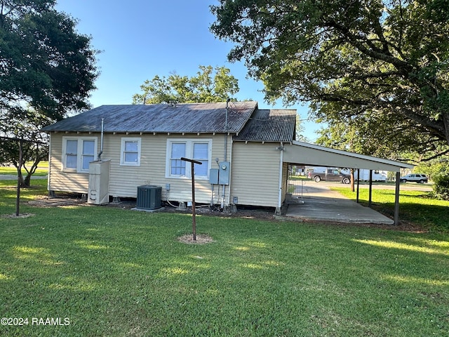 back of property with central AC unit, a lawn, and a carport