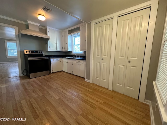 kitchen featuring wall chimney exhaust hood, wood-type flooring, white cabinetry, and electric range