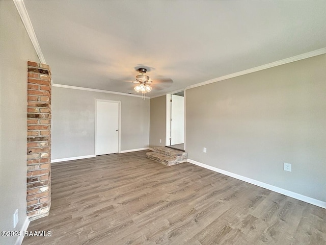 spare room featuring brick wall, wood-type flooring, ceiling fan, and ornamental molding