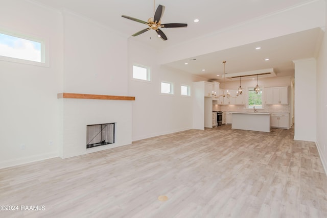 unfurnished living room with ceiling fan, light hardwood / wood-style flooring, crown molding, and sink