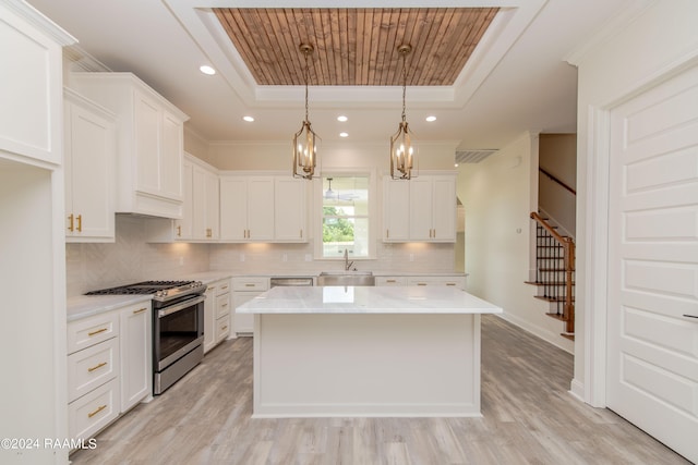 kitchen with white cabinetry, decorative light fixtures, a kitchen island, and stainless steel gas range oven