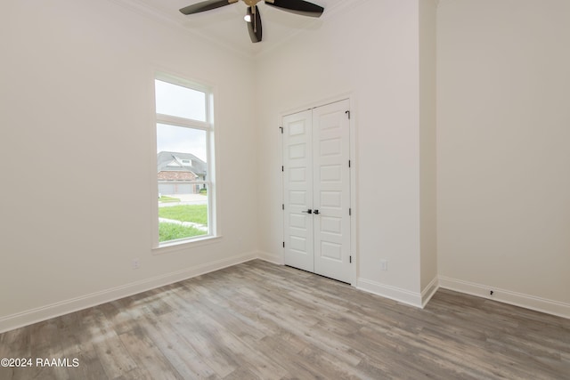 empty room with ceiling fan, light wood-type flooring, and crown molding