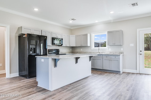 kitchen featuring black appliances, light wood-type flooring, gray cabinetry, and a kitchen island