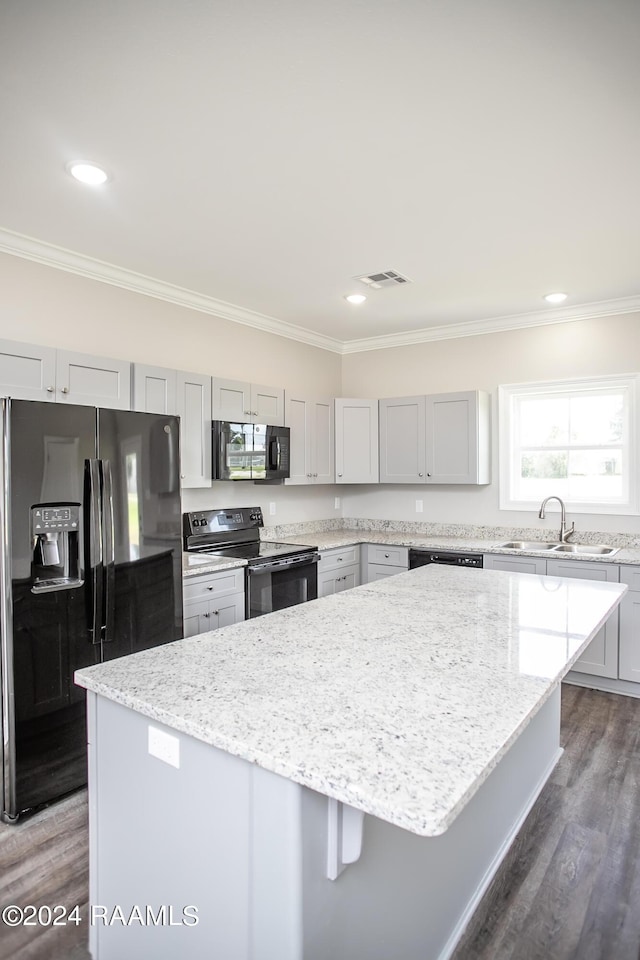 kitchen with black appliances, a center island, dark wood-type flooring, sink, and light stone counters