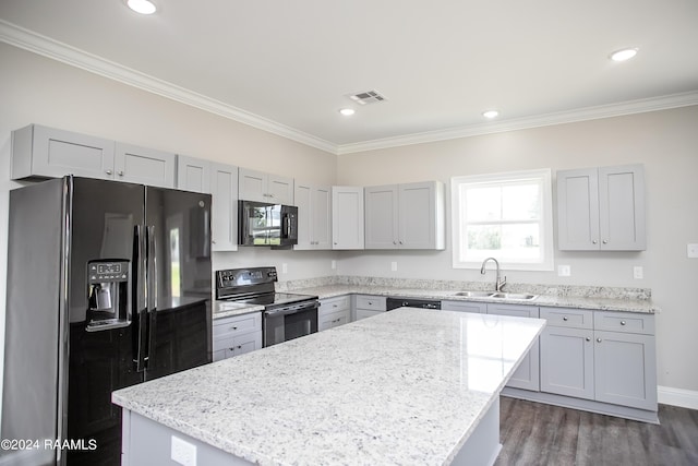 kitchen featuring black appliances, a center island, light stone countertops, crown molding, and sink