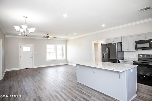 kitchen featuring light stone countertops, black appliances, a center island, a kitchen breakfast bar, and ornamental molding