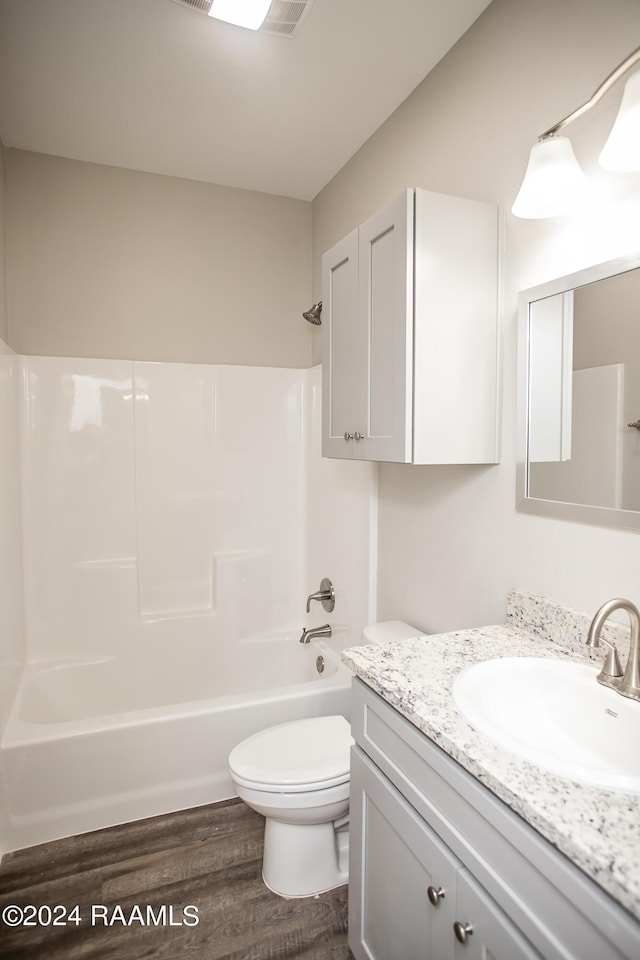 full bathroom featuring washtub / shower combination, wood-type flooring, toilet, and vanity