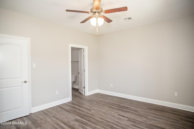 unfurnished bedroom with ceiling fan, dark wood-type flooring, and a walk in closet