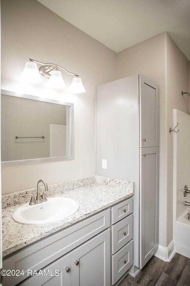 bathroom featuring hardwood / wood-style flooring, vanity, and bathing tub / shower combination