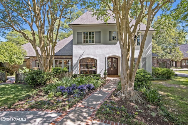 view of front of house with stucco siding, a front yard, and roof with shingles