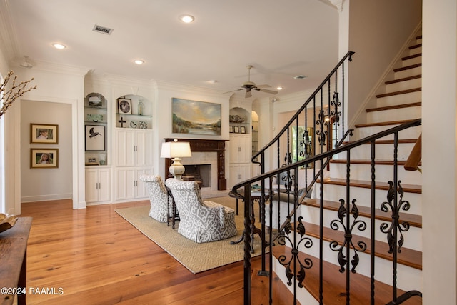 interior space with built in features, ceiling fan, light hardwood / wood-style floors, and ornamental molding