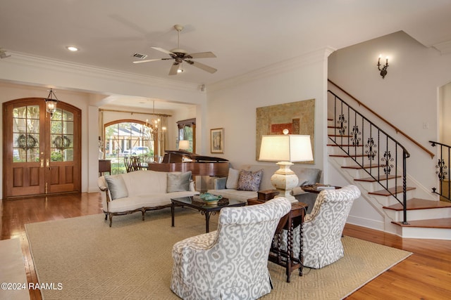 living room with french doors, ornamental molding, ceiling fan with notable chandelier, and hardwood / wood-style floors