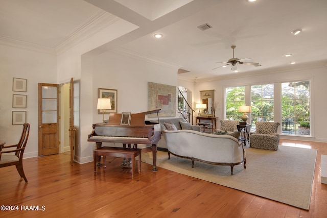 living room featuring wood-type flooring, ceiling fan, and crown molding