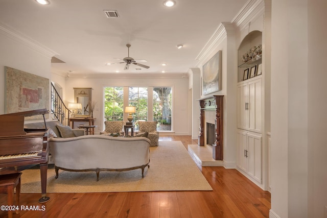 living room with light hardwood / wood-style floors, ornamental molding, and ceiling fan