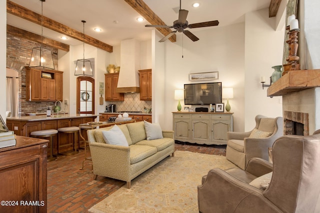 living room with beam ceiling, ceiling fan, and a brick fireplace